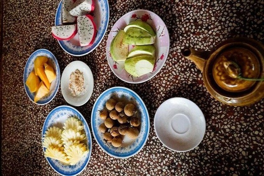 A variety of fruits and a teapot on a patterned tablecloth. 5