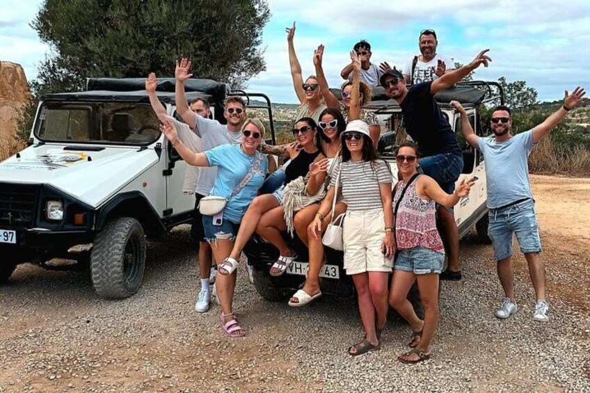 A group of people posing in front of a white off-road vehicle with a license plate number 97-43. 2