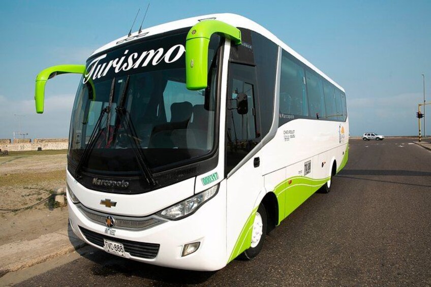 A white and green bus with 'Turismo' written on the front, driving on a road. 3