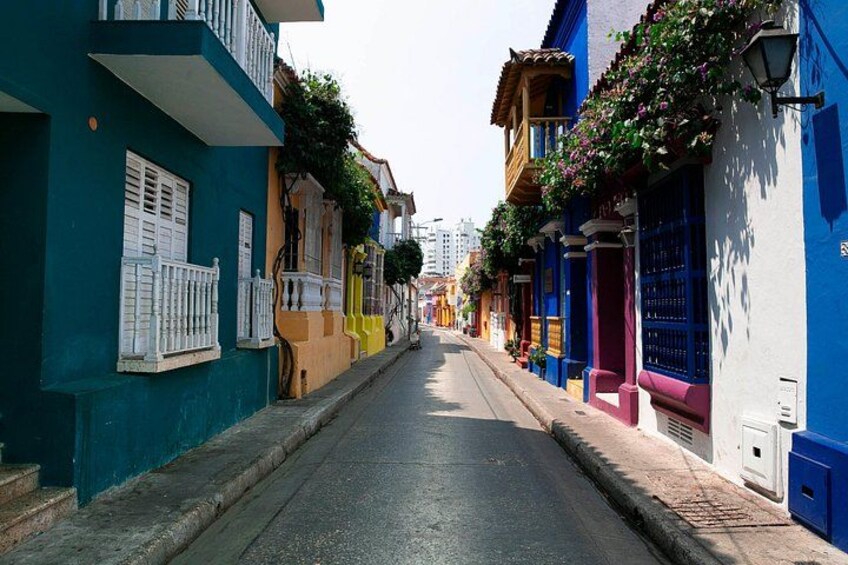 A narrow street lined with colorful buildings, some with balconies and flower boxes. 2
