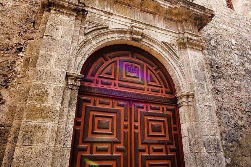 A large, ornate wooden door with intricate carvings, set within a stone archway. 3