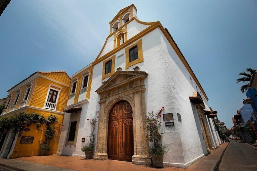 A historic building with a large wooden door, a bell tower, and a white facade. 4