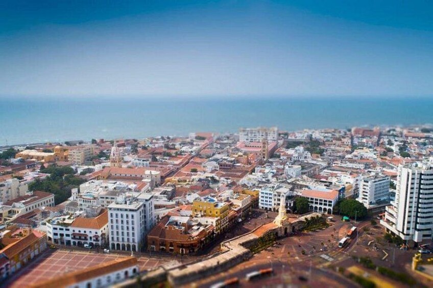 A coastal cityscape with a prominent church, a mix of modern and traditional buildings, and a clear view of the ocean. 4