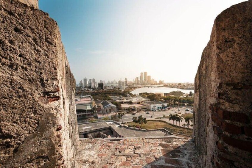A cityscape with a large rock formation in the foreground and a river in the background. 2