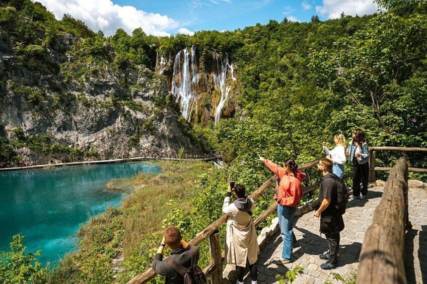 A group of visitors points excitedly at the cascading waterfalls in Plitvice, capturing the awe-inspiring power and beauty of Croatia’s iconic park. 3