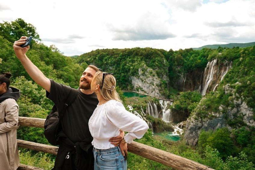 Visitors stand in awe in front of the majestic waterfalls at Plitvice Lakes National Park in Croatia, surrounded by stunning scenic beauty, a top-rated travel experience in Europe. 2