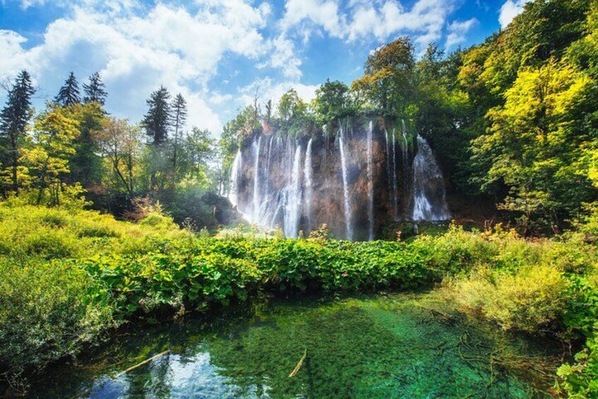 Golden sunlight shines over a majestic Plitvice waterfall, highlighting the mist and greenery — a magical moment 2