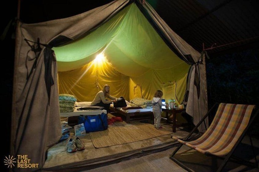 Een tent met een slaapgedeelte, een kind en een persoon die op de grond zit. 5