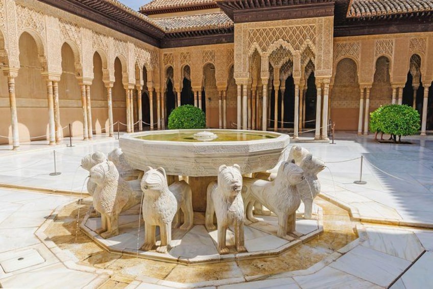 Une cour avec une fontaine, entourée de statues de lions, d’arcades et d’un sol carrelé. 3