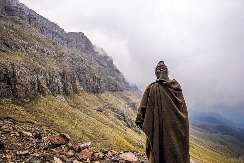 A person standing on a rocky outcrop overlooking a mountainous landscape. 3