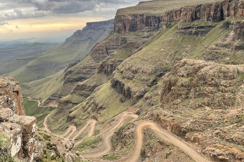 A winding mountain road with steep cliffs and a valley below. 5