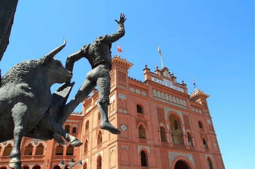 A building with a red facade and a sign that reads 'Plaza de Toros.' 5
