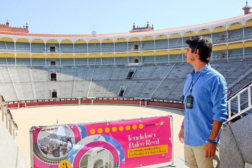 An empty bullring with a man standing near the entrance. 4