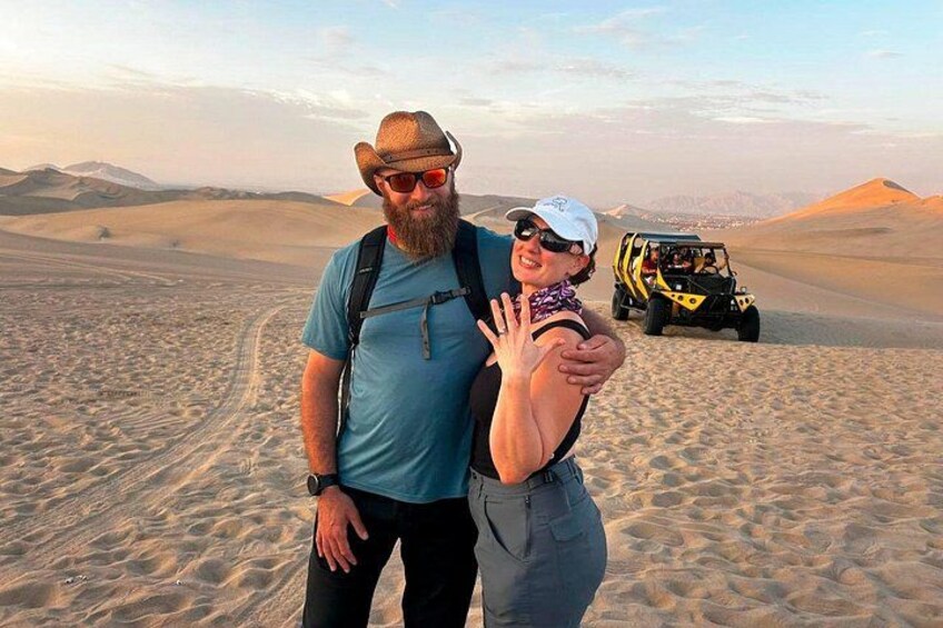 To personer i en ørken med sandklitter og en sandbuggy i baggrunden. 2