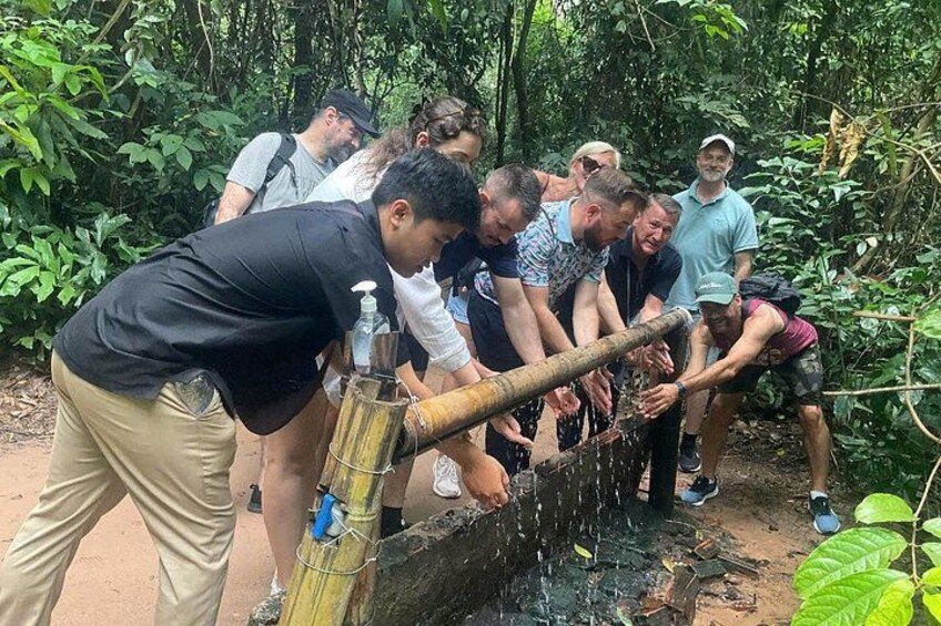 A group of people using a bamboo water pump in a forested area. 5