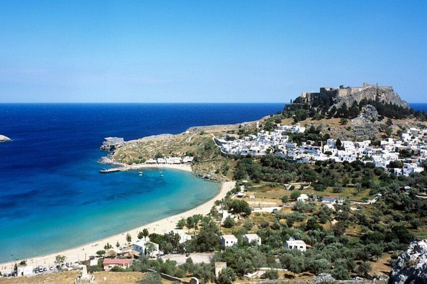 A coastal town with a castle on a hill, a beach, and white houses. 3