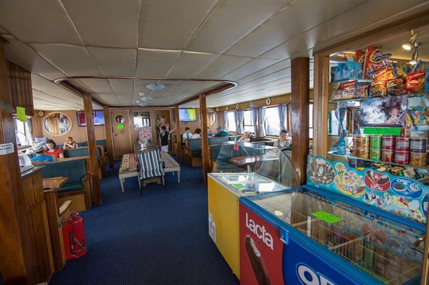 Comedor de crucero con paneles de madera, una mesa central y un bar de aperitivos con diferentes opciones de comida. 2