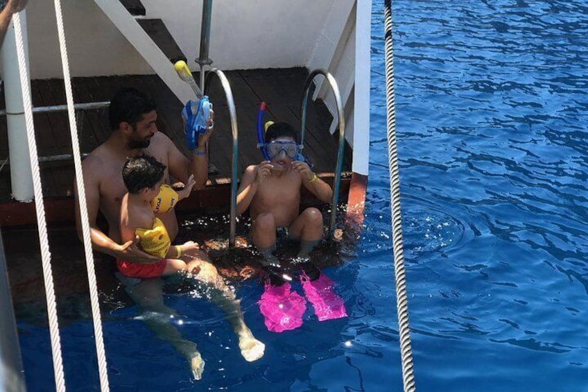 Una piscina con gente sentada y de pie, usando trajes de baño y gafas de natación. 2