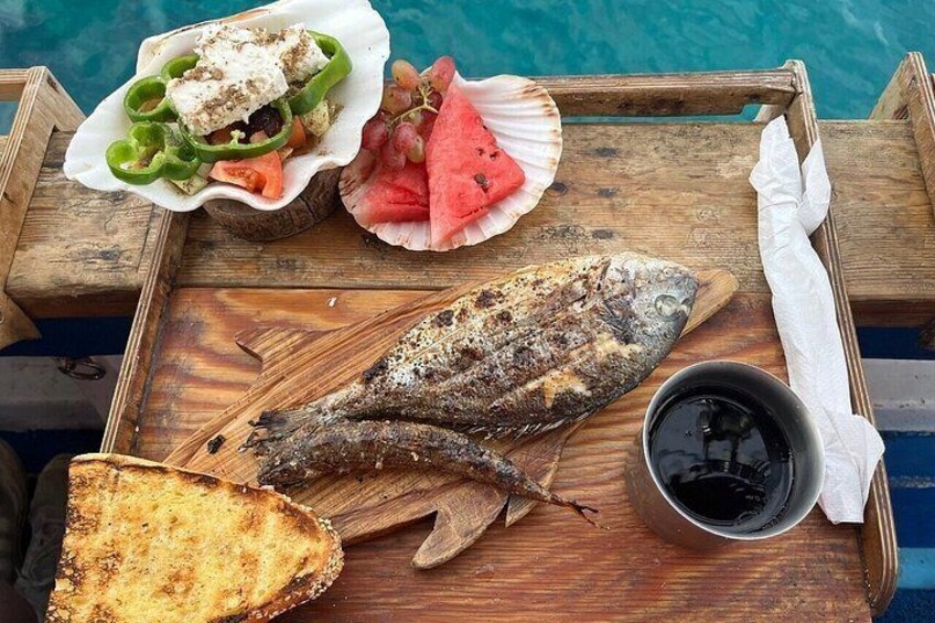 A wooden tray with grilled fish, a salad, and a slice of bread by a pool. 2