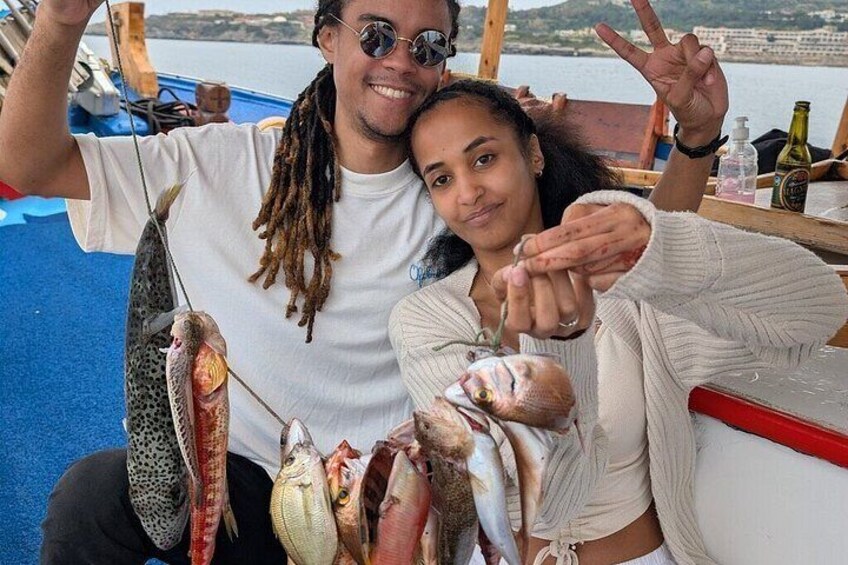 A person holding multiple fish, a boat, and a body of water in the background. 5