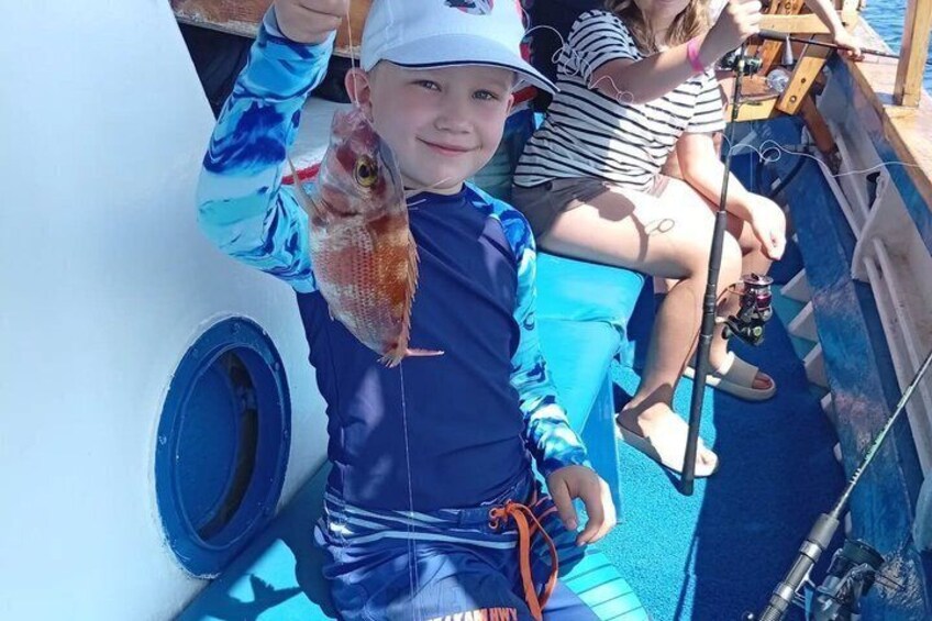 A person holding a fish on a boat. 1