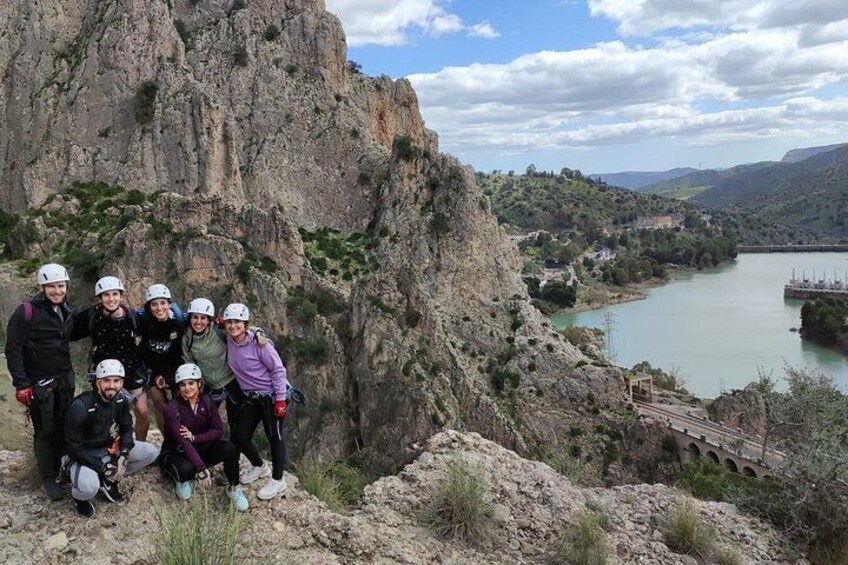 A group of people with helmets, a rocky cliff, and a river. 2