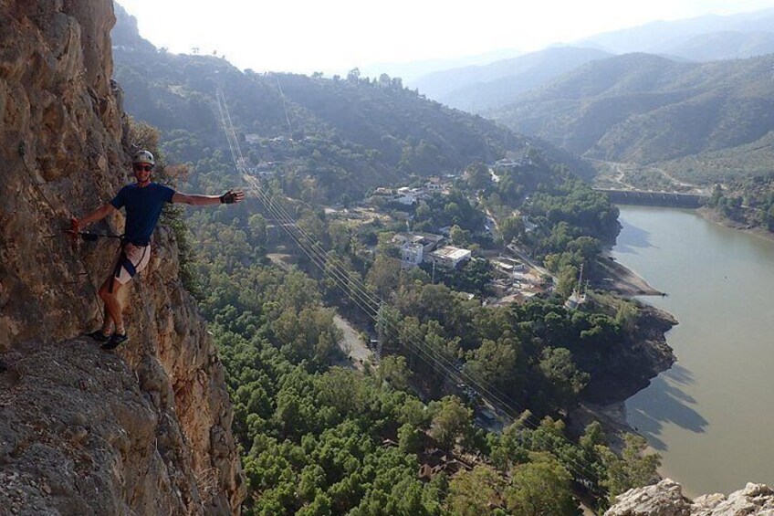 A person rappelling down a cliff with a river and mountains in the background. 3