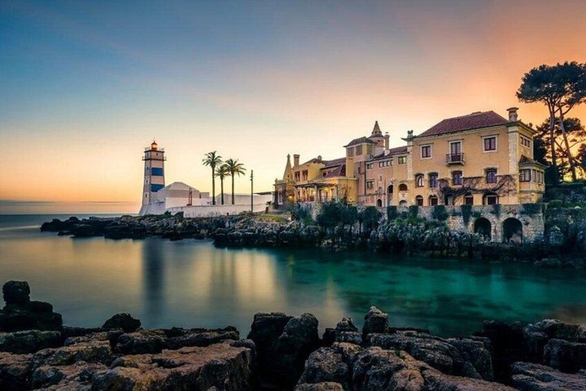 Un pueblo costero con un faro, edificios históricos y un mar tranquilo al atardecer. 2