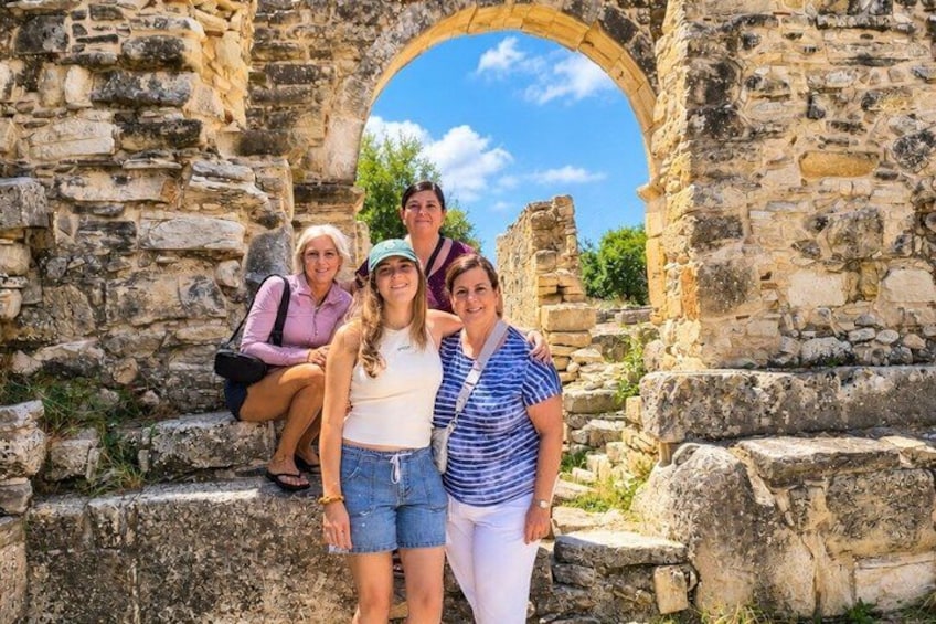 A group of people standing in front of ancient stone ruins with an archway. 5