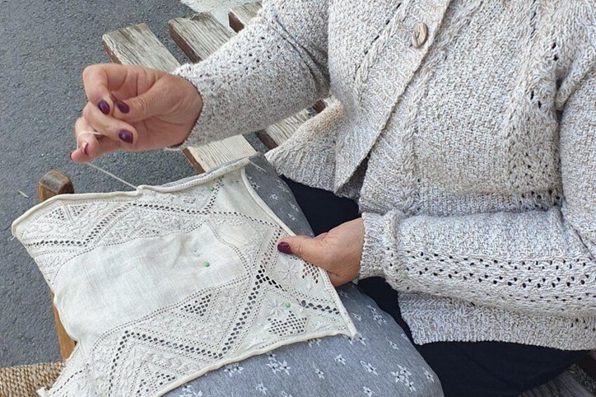 A person sitting on a wooden bench, holding a white crocheted bag. 5