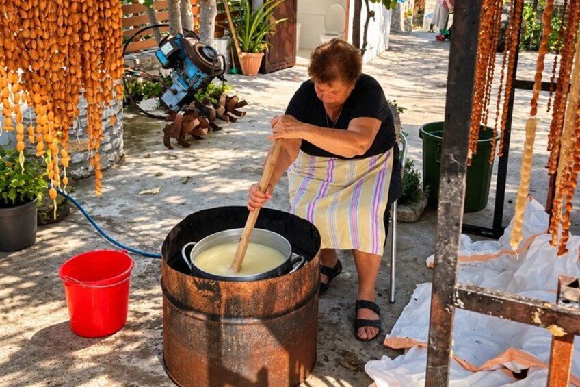 A person stirring a large pot outdoors. 2