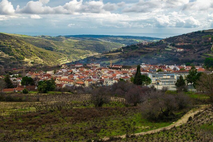 A town nestled in a valley with vineyards, rolling hills, and a clear sky. 1