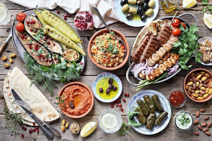 A variety of Middle Eastern dishes including kebabs, hummus, and stuffed grape leaves. 2