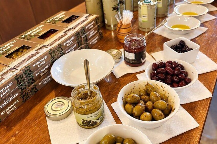 Une table avec des pots d’olives, de l’huile d’olive et d’autres condiments, ainsi que des boîtes d’huile d’olive. 4
