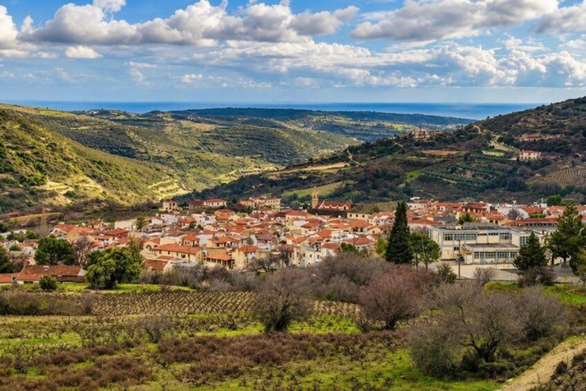 Une ville nichée dans une vallée, avec des bâtiments aux toits rouges, entourée de collines et de vignobles. 5