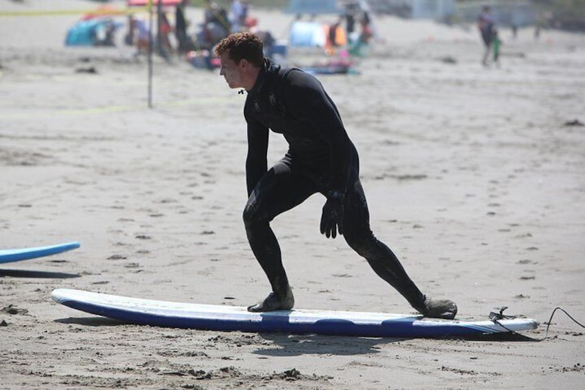 A person in a wetsuit on a surfboard at the beach. 5