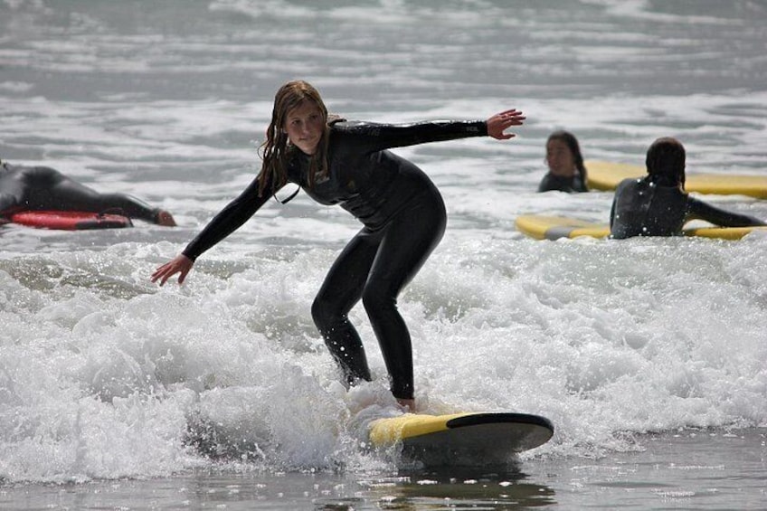 A person surfing on a wave with other surfers in the background. 2