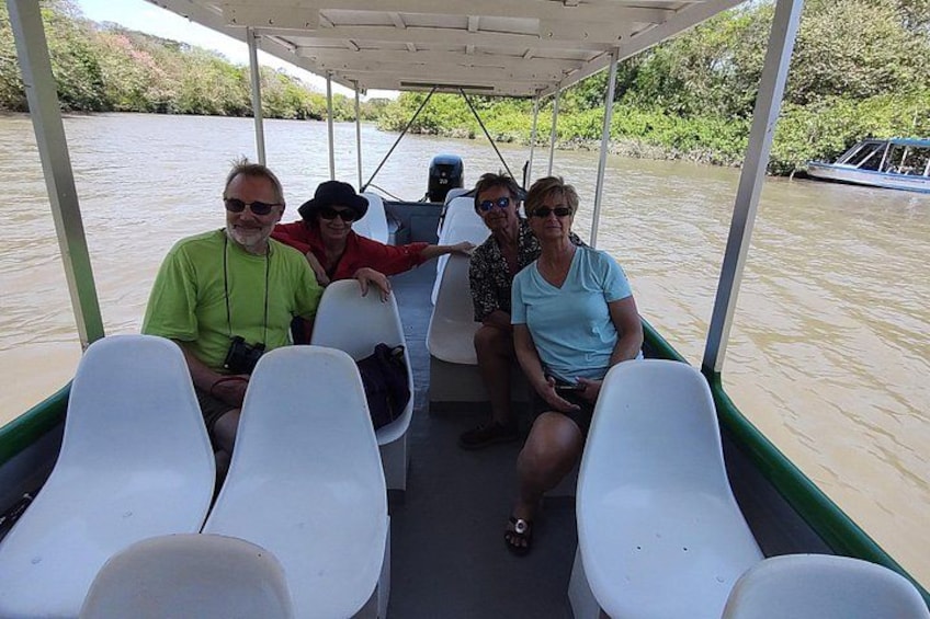 A group of people on a boat with white seats and a covered area. 5