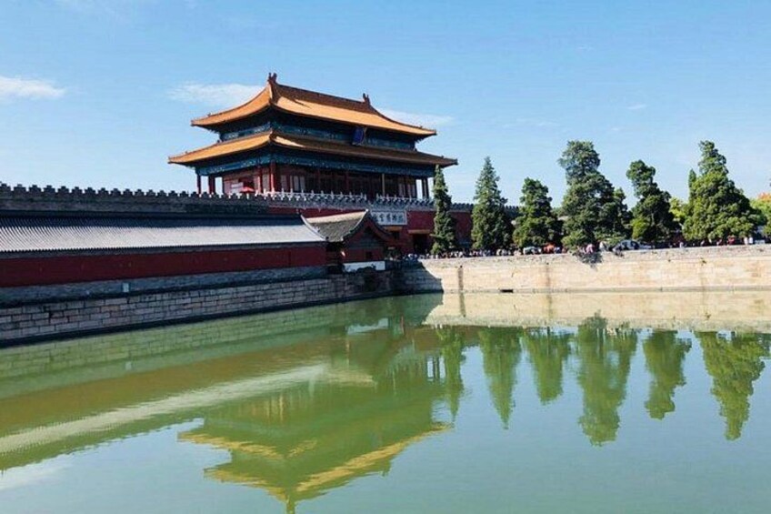 Un edificio tradicional chino con tejado de baldosas, un reflejo en el agua y un muro de piedra. 3
