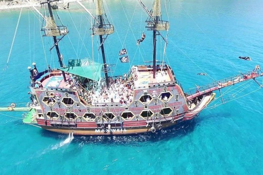 Een groot, versierd schip met meerdere masten en een kleurrijk, gedetailleerd ontwerp, drijvend op helderblauw water. 4