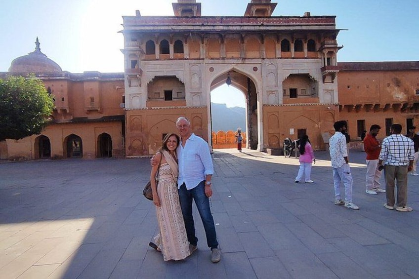 A historical building with an archway, a dome, and a courtyard with people. 2