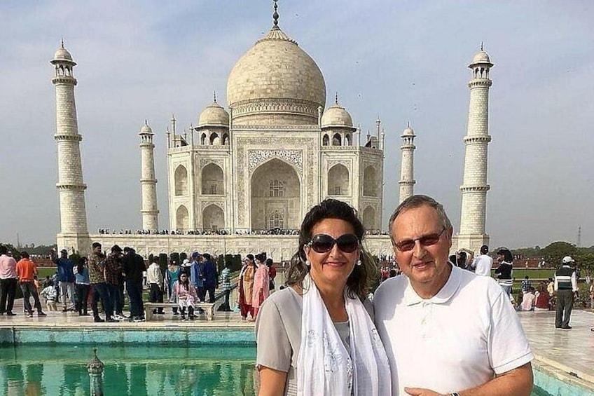 A couple standing in front of the Taj Mahal with a crowd in the background. 3