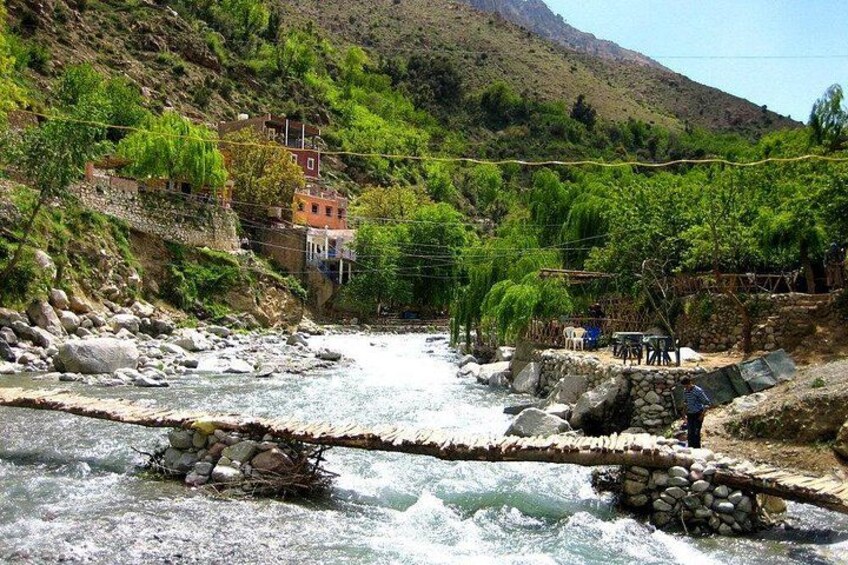 A river with a bridge, houses, and a mountainous landscape. 1