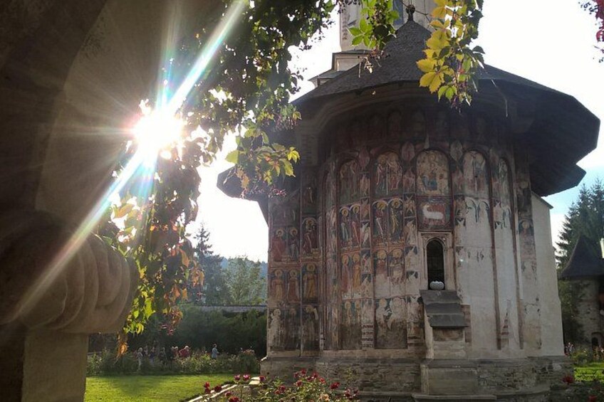 A historic building with intricate frescoes, surrounded by a well-maintained garden. 4