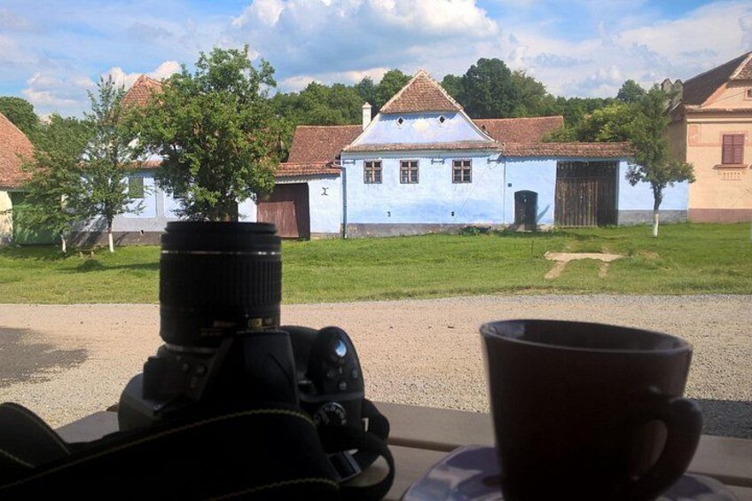 A camera with a lens, a coffee cup, and a rural landscape with houses. 2