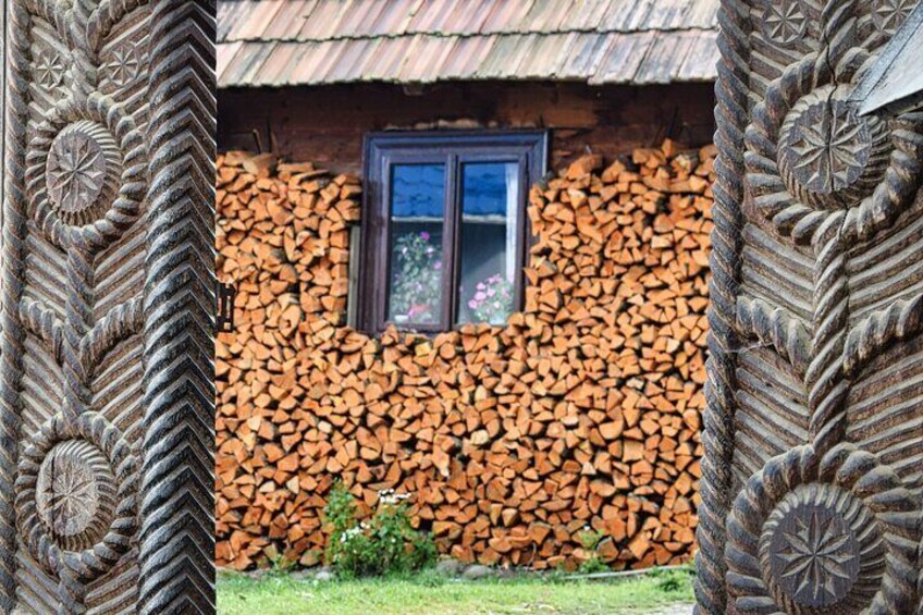A rustic building with a thatched roof, a window, and a wall of stacked logs. 3
