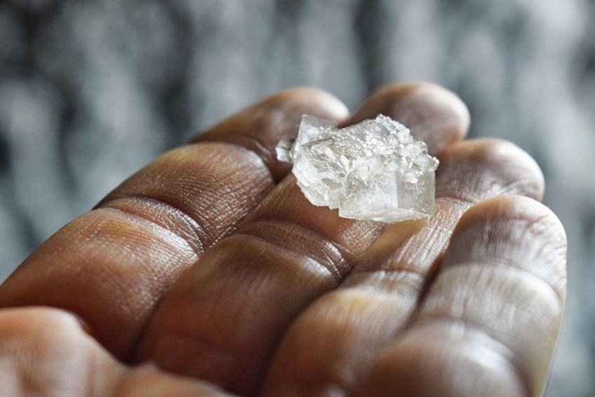 Eine Hand hält ein klares, kristallines Mineral. 5