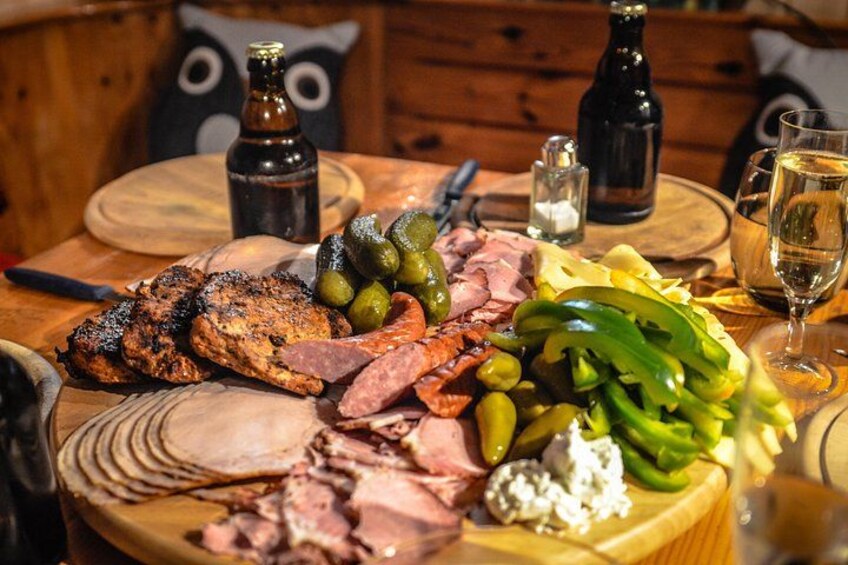 A wooden table with a variety of meats, olives, and vegetables. 2