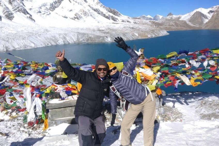 Two people in a snowy landscape with a lake and mountains in the background. 1