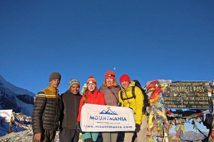 Un grupo de personas de pie en una montaña, con un cartel que dice 'MOUNTAIN MANIA' y un letrero que indica 'THORNHILL PASS'. 1